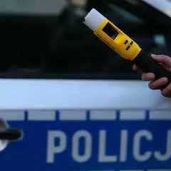 Dłoń trzyma żółty alkomat na tle radiowozu z napisem POLICJA. Czy mogę odmówić dmuchania w alkomat?