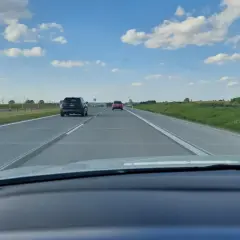 Widok z samochodu na autostradzie. Widać inne pojazdy i znaki ograniczające prędkość do 80 km/h.