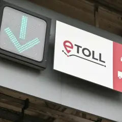 Zielony znak ze strzałkami w dół i logo e-TOLL. Informuje, jak zapłacić za autostradę, wskazując drogę dla samochodów i ciężarówek.