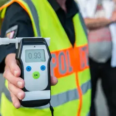 Policjant pokazuje alkomat z wynikiem 0.93 promila. To pokazuje, ile jest dozwolone alkoholu w wydychanym powietrzu.
