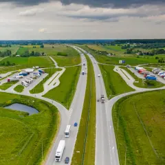 Miejsce obsługi podróżnych (MOP) na autostradzie, z parkingiem dla ciężarówek i samochodów osobowych, otoczone zielenią.