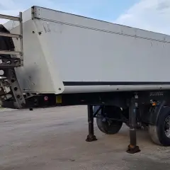 Biała naczepa Schmitz na kołach, z drabiną z boku. Zastanawiasz się, ile waży tir z naczepą na pusto?