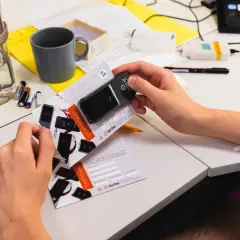 Ręce trzymające alkomat i certyfikat kalibracji na biurku z laboratoryjnym sprzętem.