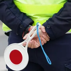 Policjant w kamizelce odblaskowej trzyma znak stop. Zastanawiasz się, ile km można jechać na autostradzie?