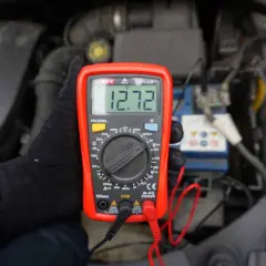Multimetr pokazuje 12.72V, co jest kluczowe, jak poznać że akumulator jest naładowany. Sprawdzanie napięcia to prosty sposób na ocenę stanu baterii.