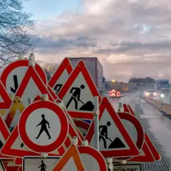 Znaki drogowe ostrzegają: roboty w toku, kiedy trzeba zachować szczególną ostrożność. Ruch spowolniony, mokra nawierzchnia.