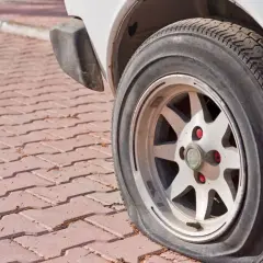 Zapieczone koło samochodu na czerwonej kostce brukowej. Dowiedz się, jak zdjąć zapieczone koło, gdy napotkasz taki problem.