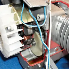 Wnętrze urządzenia, które ładuje akumulator w skuterze: widać wirnik, cewki, zębatkę i przewody.
