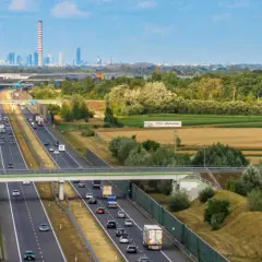 Autostrada z ruchem samochodowym i widocznym w oddali miastem. Pytanie: z jaką prędkością masz obowiązek jechać na autostradzie?