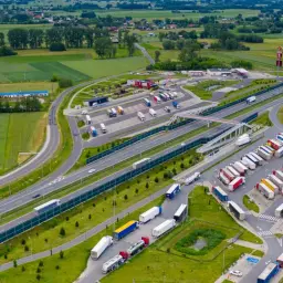 Parking dla ciężarówek przy autostradzie. Czy to MOP? Tak, to skrót od Miejsce Obsługi Podróżnych. Widać Orlen, KFC i wiele tirów.