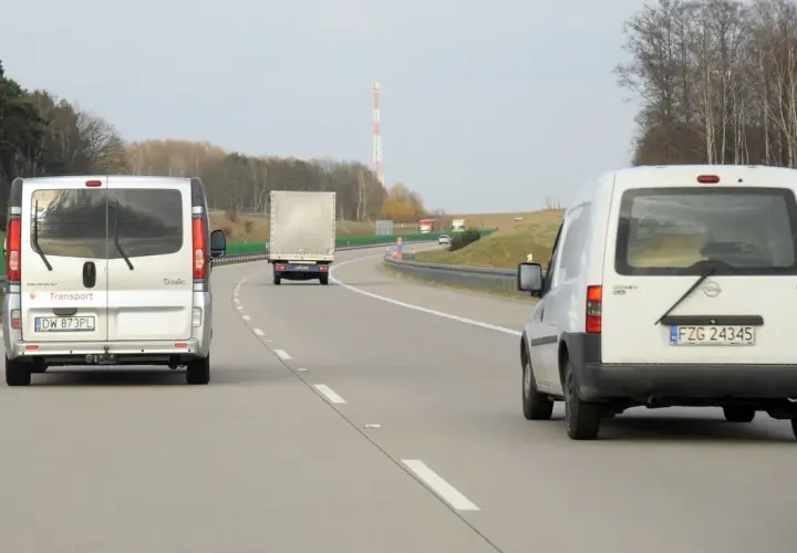 Na autostradzie widać kilka pojazdów, w tym dwa białe busy i jeden tir. Zastanawiasz się, ile tir może jechać na autostradzie?