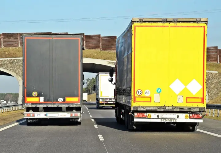 Na autostradzie jadą trzy tiry. Znak ograniczenia prędkości wskazuje, że tiry mogą jechać 70 lub 80 km/h.