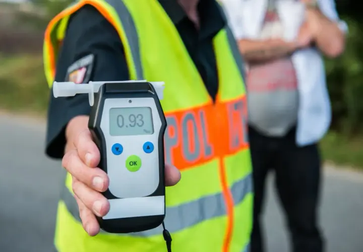 Policjant pokazuje alkomat z wynikiem 0.93 promila. To pokazuje, ile jest dozwolone alkoholu w wydychanym powietrzu.