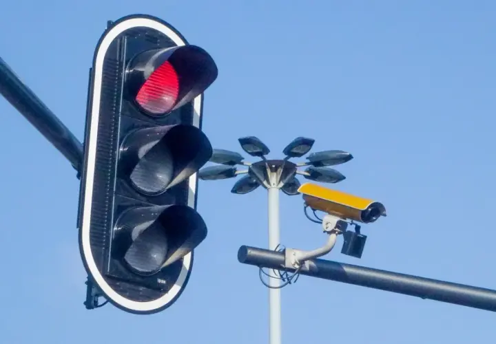 Czerwone światło na sygnalizatorze i żółta kamera monitorująca ruch. Te kamery na sygnalizacji świetlnej dbają o bezpieczeństwo.