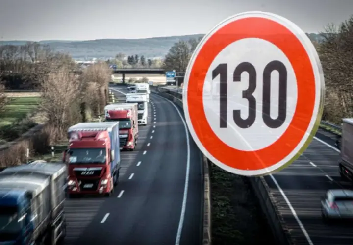 Znak ograniczenia prędkości 130 km/h na niemieckiej autostradzie. Widać sznur ciężarówek jadących w korku.