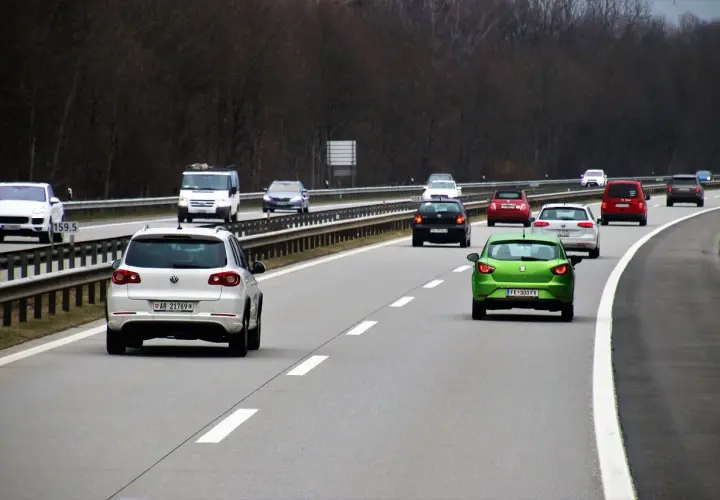 Ruch na autostradzie. Kierowca zielonego auta zastanawia się, jaki mandat za wymuszenie pierwszeństwa, gdyby to zrobił.
