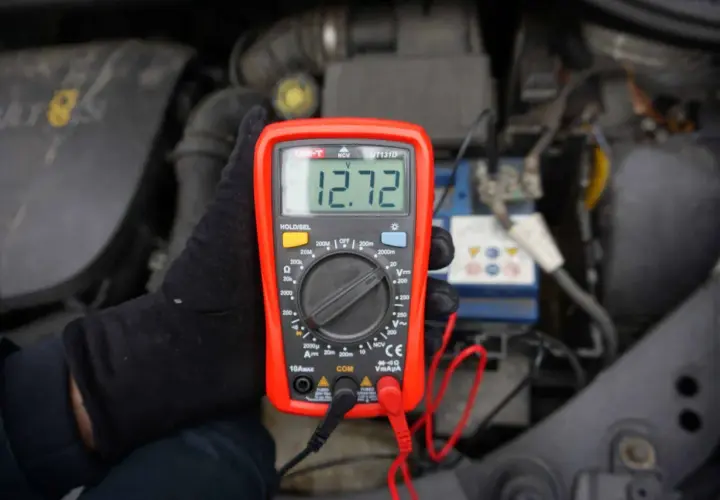 Multimetr pokazuje 12.72V, co jest kluczowe, jak poznać że akumulator jest naładowany. Sprawdzanie napięcia to prosty sposób na ocenę stanu baterii.