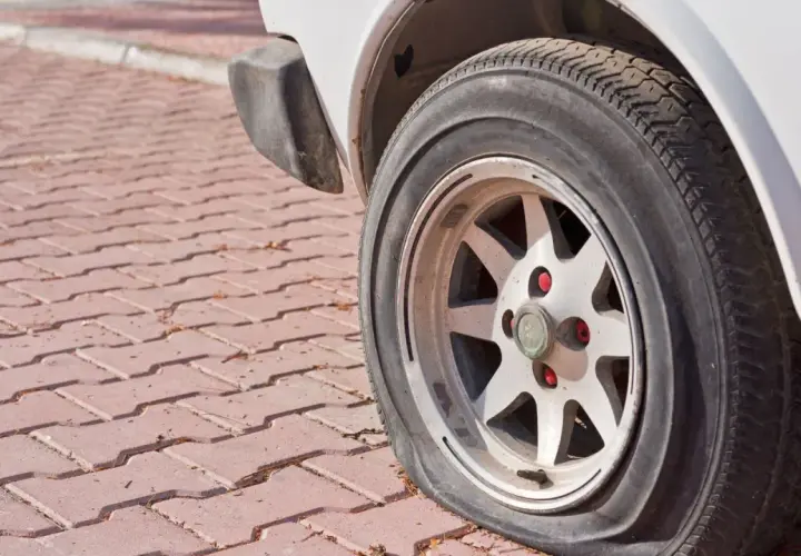 Zapieczone koło samochodu na czerwonej kostce brukowej. Dowiedz się, jak zdjąć zapieczone koło, gdy napotkasz taki problem.