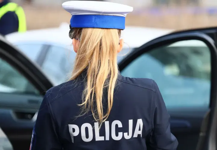 Policjantka w granatowym mundurze z napisem "POLICJA" na plecach, w białej czapce z niebieskim otokiem. Zastanawia się, ile pkt za pasy.