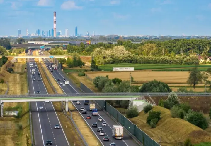 Autostrada z ruchem samochodowym i widocznym w oddali miastem. Pytanie: z jaką prędkością masz obowiązek jechać na autostradzie?