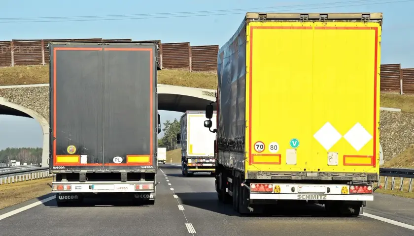 Na autostradzie jadą trzy tiry. Znak ograniczenia prędkości wskazuje, że tiry mogą jechać 70 lub 80 km/h.