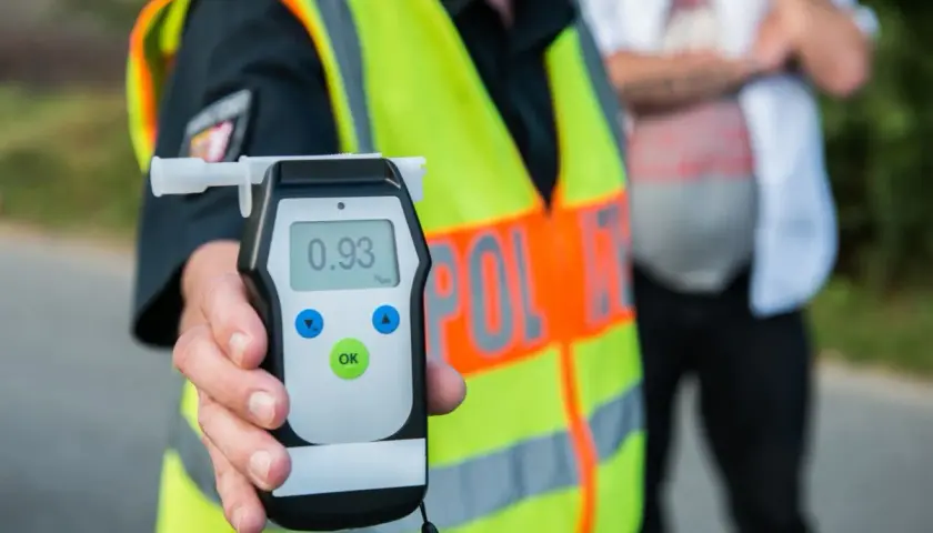 Policjant pokazuje alkomat z wynikiem 0.93 promila. To pokazuje, ile jest dozwolone alkoholu w wydychanym powietrzu.