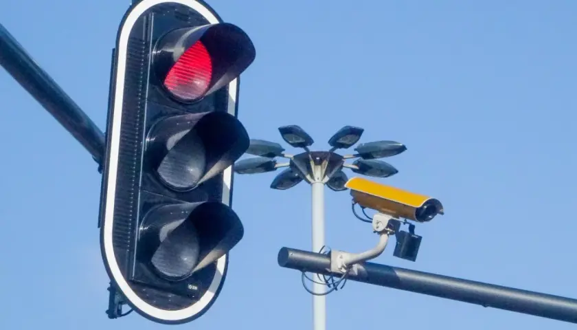 Czerwone światło na sygnalizatorze i żółta kamera monitorująca ruch. Te kamery na sygnalizacji świetlnej dbają o bezpieczeństwo.
