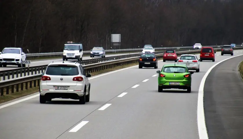 Ruch na autostradzie. Kierowca zielonego auta zastanawia się, jaki mandat za wymuszenie pierwszeństwa, gdyby to zrobił.