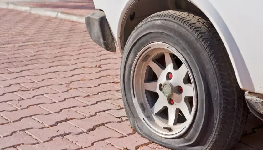Zapieczone koło samochodu na czerwonej kostce brukowej. Dowiedz się, jak zdjąć zapieczone koło, gdy napotkasz taki problem.