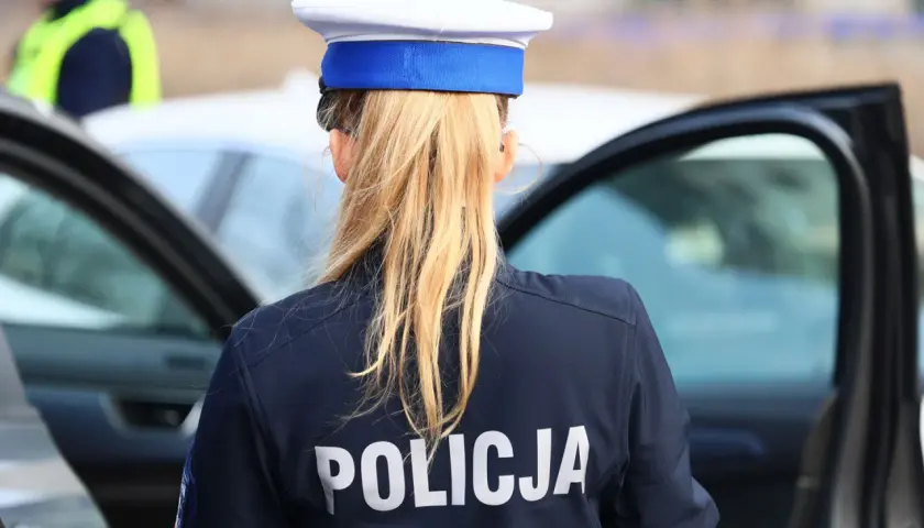 Policjantka w granatowym mundurze z napisem "POLICJA" na plecach, w białej czapce z niebieskim otokiem. Zastanawia się, ile pkt za pasy.
