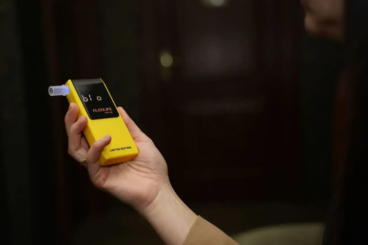 Dłoń trzyma żółty alkomat z wyświetlaczem. Czy w Żabce są alkomaty? Ten model jest limitowaną edycją.