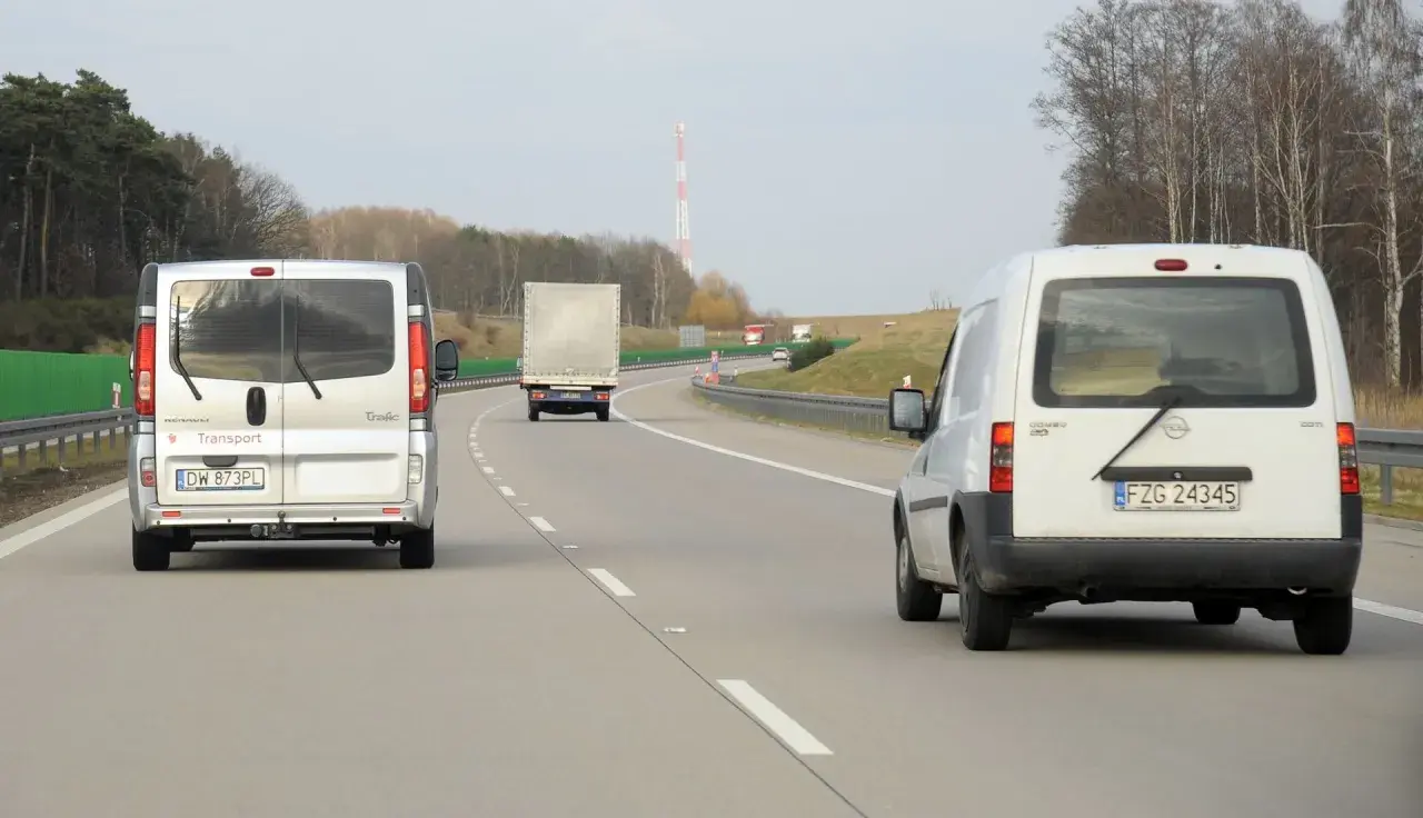 Na autostradzie widać kilka pojazdów, w tym dwa białe busy i jeden tir. Zastanawiasz się, ile tir może jechać na autostradzie?