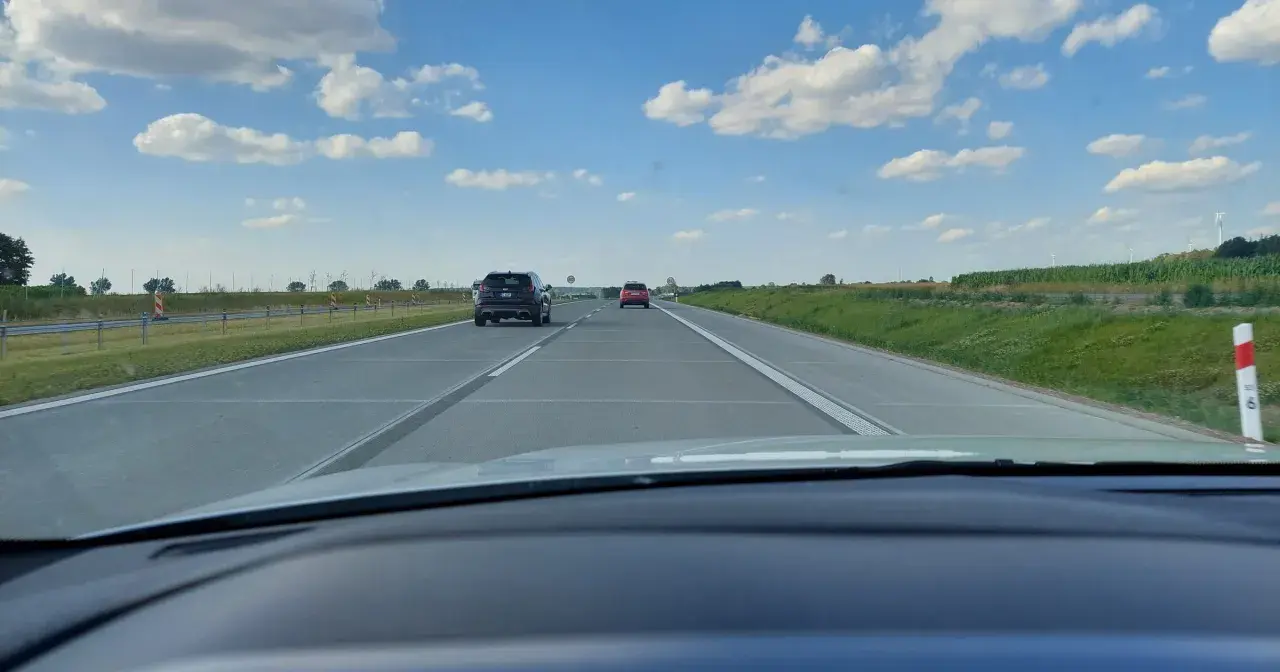 Widok z samochodu na autostradzie. Widać inne pojazdy i znaki ograniczające prędkość do 80 km/h.