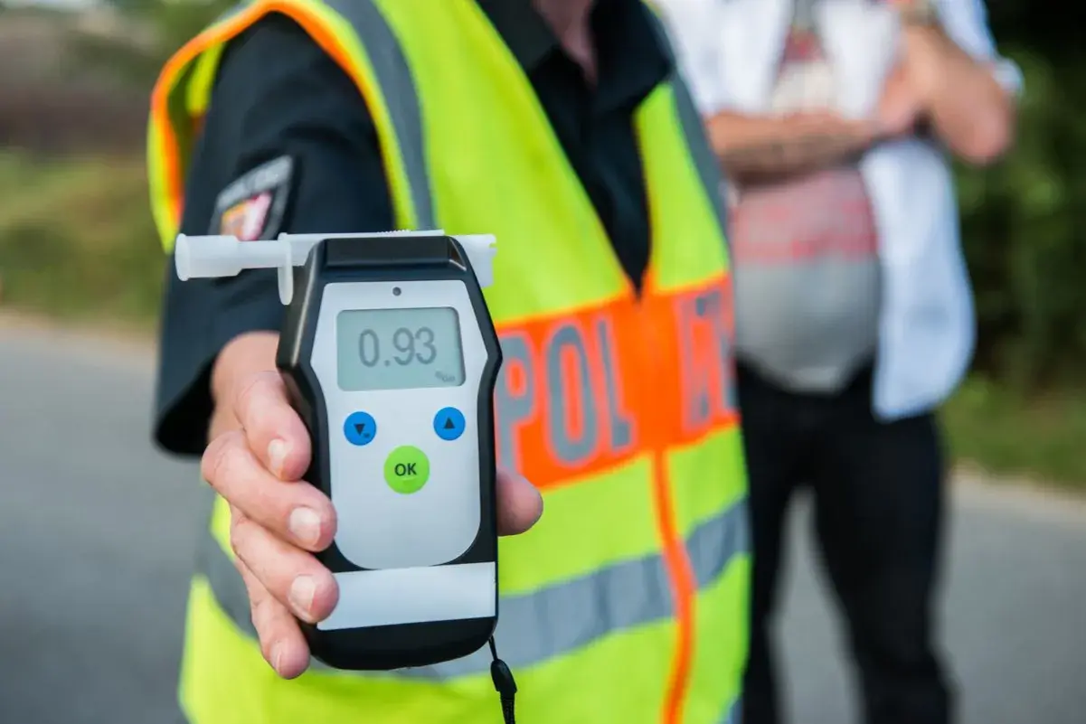 Policjant pokazuje alkomat z wynikiem 0.93 promila. To pokazuje, ile jest dozwolone alkoholu w wydychanym powietrzu.