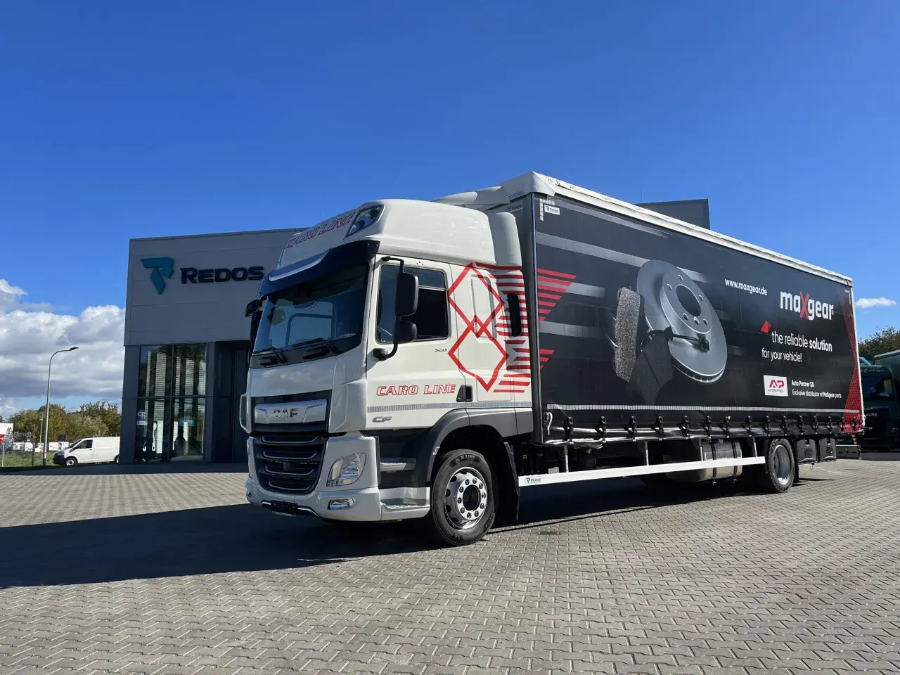 Biała ciężarówka DAF z naczepą reklamującą części samochodowe Maxgear. Długość tej ciężarówki to ok. 13,6 metra.