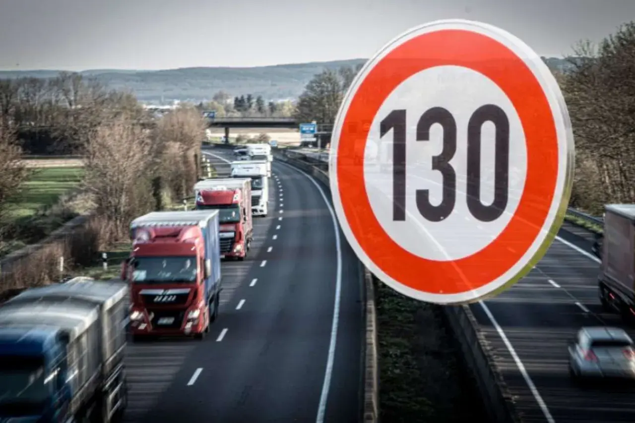 Znak ograniczenia prędkości 130 km/h na niemieckiej autostradzie. Widać sznur ciężarówek jadących w korku.