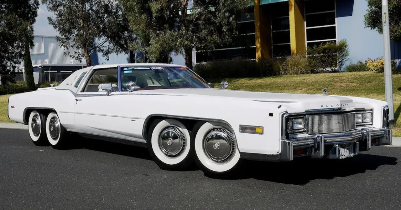 Biały Cadillac Eldorado z podwójnymi kołami z przodu i z tyłu. Ten niezwykły samochód ma aż cztery osie, co czyni go wyjątkowym na drodze.