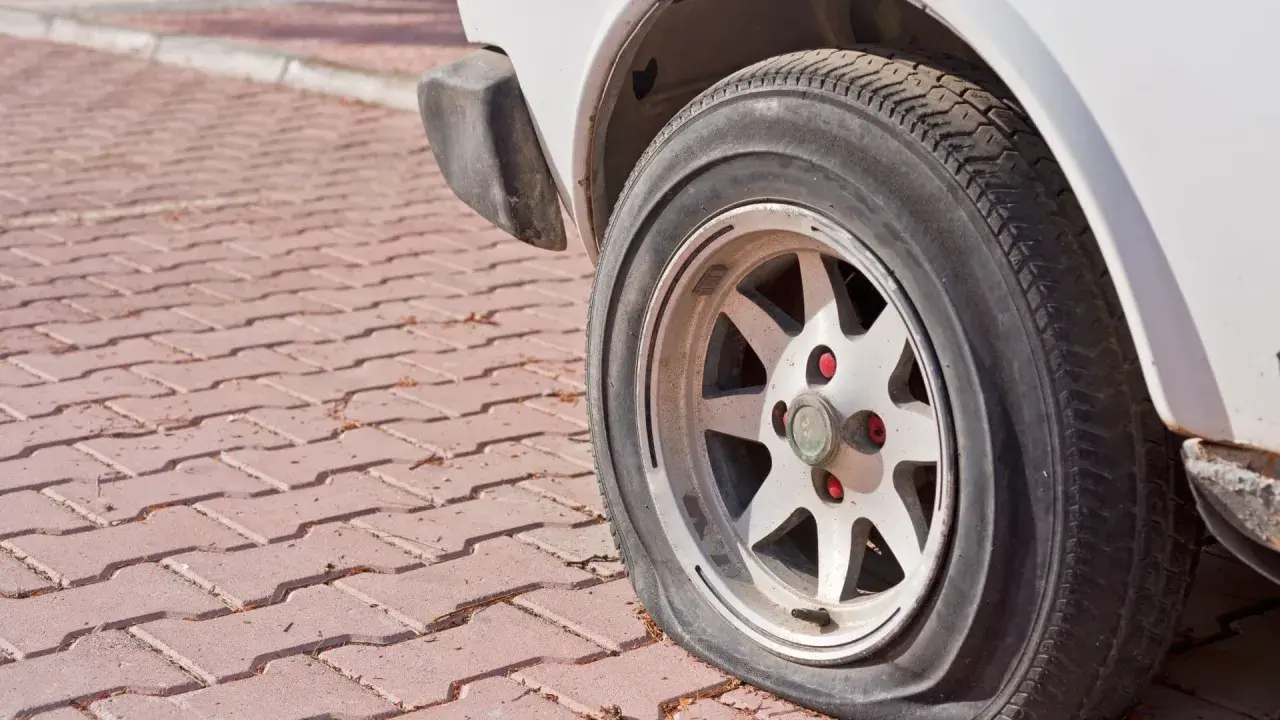 Zapieczone koło samochodu na czerwonej kostce brukowej. Dowiedz się, jak zdjąć zapieczone koło, gdy napotkasz taki problem.
