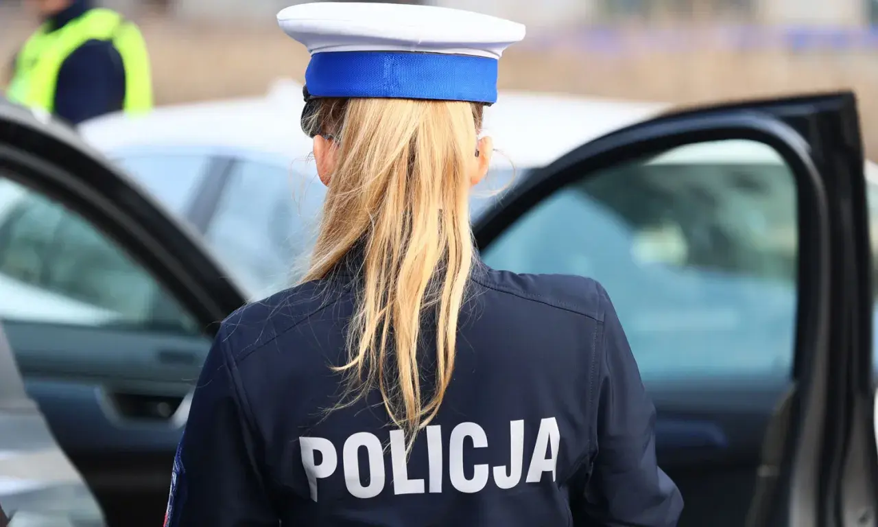 Policjantka w granatowym mundurze z napisem "POLICJA" na plecach, w białej czapce z niebieskim otokiem. Zastanawia się, ile pkt za pasy.