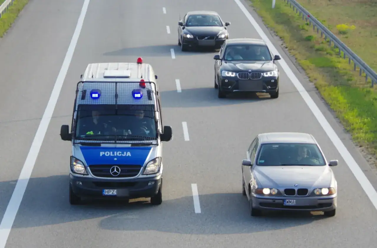 Policyjny van z włączonymi sygnałami jedzie autostradą. Obok jadą inne samochody. Czy to pościg?