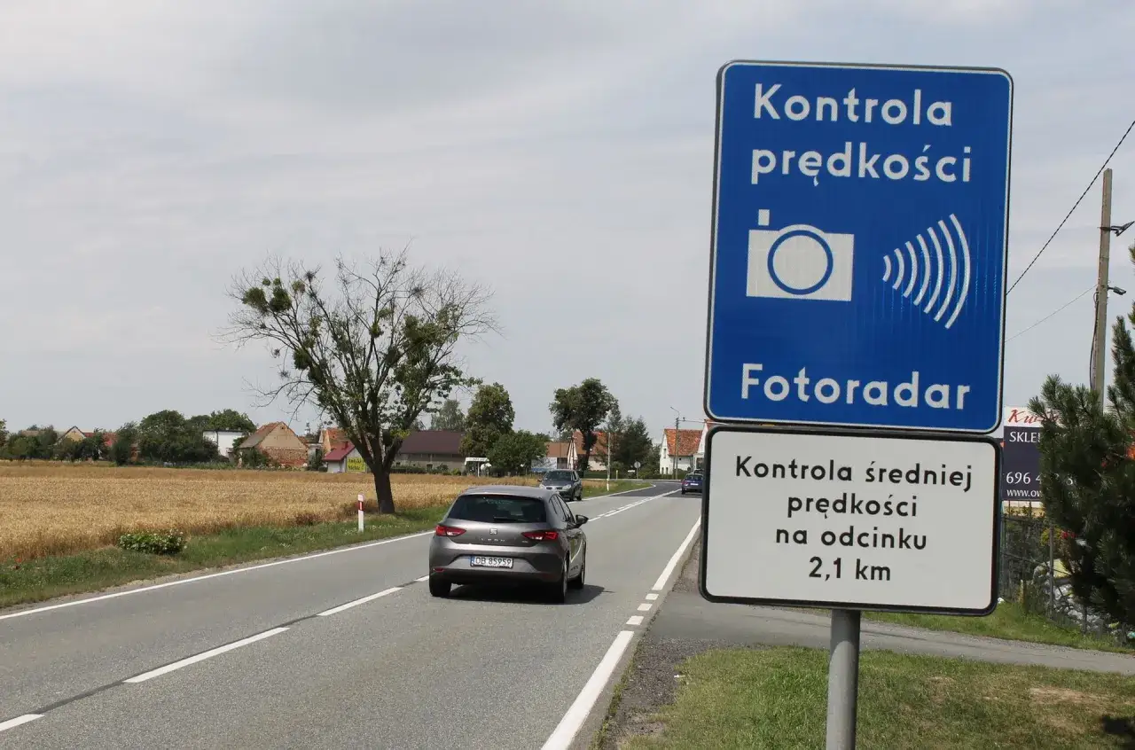 Znak informuje o kontroli prędkości fotoradarem na odcinku 2,1 km. Samochód zbliża się do miejsca, gdzie może być mierzona jego prędkość.