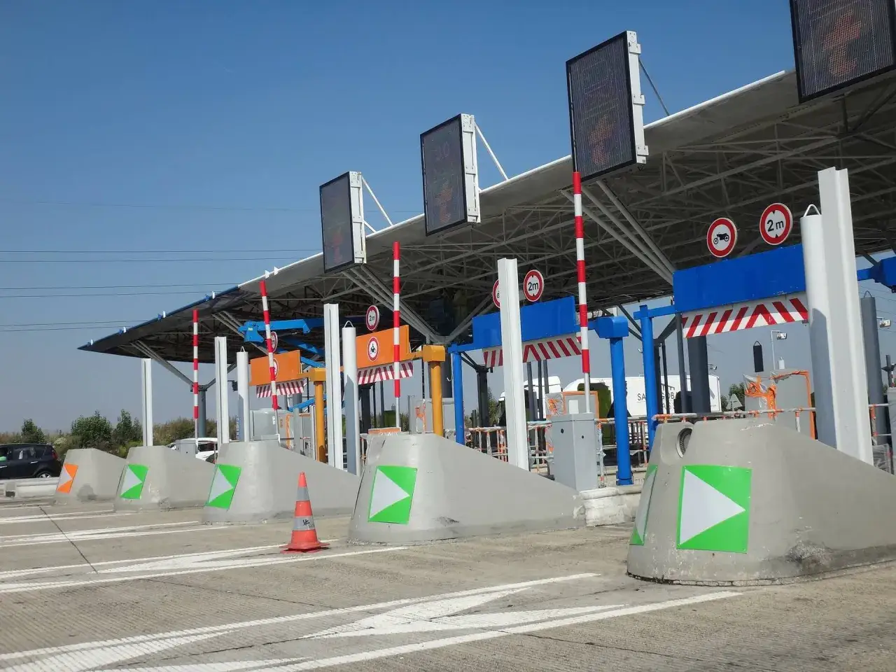 Płatne autostrady we Francji? Tak, widać tu bramki poboru opłat z tablicami informacyjnymi i zielonymi strzałkami.