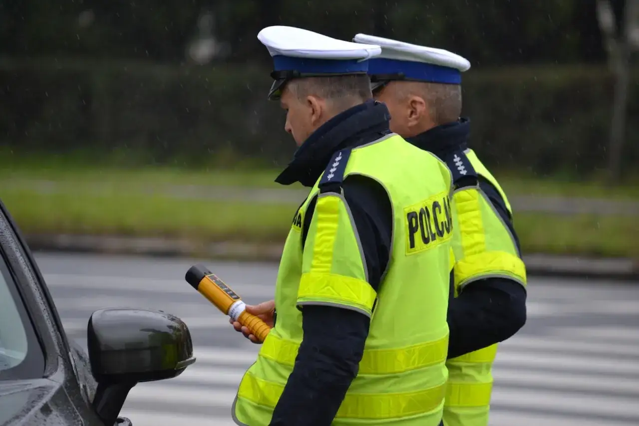 Policjant w kamizelce odblaskowej trzyma alkomat. Czy mogę odmówić dmuchania w alkomat? Deszcz pada.