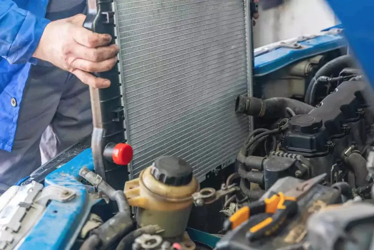 Mechanik wymienia chłodnicę w samochodzie. To kluczowy element układu chłodzenia, który zapobiega przegrzewaniu się silnika.