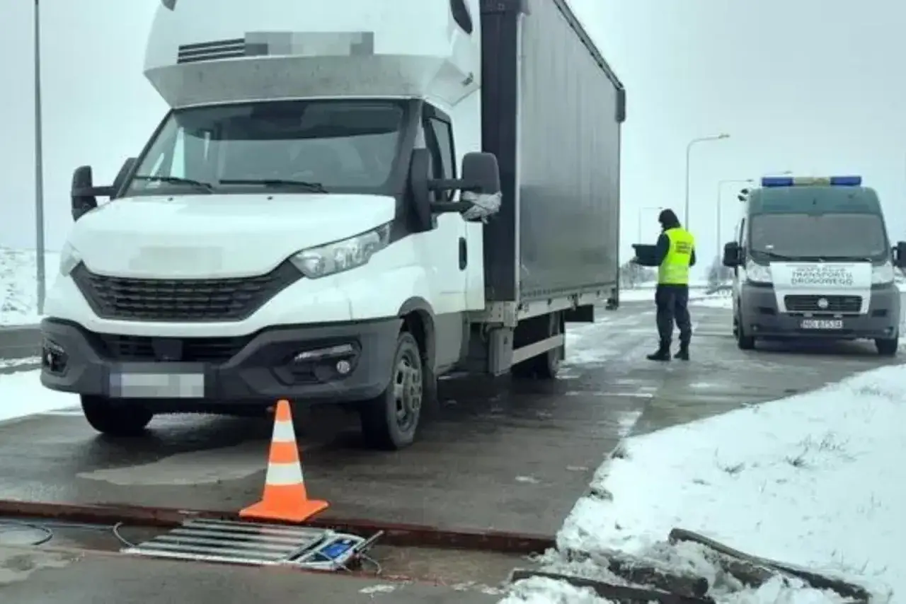 Kontrola drogowa: biała ciężarówka na wadze. Pracownik w kamizelce odczytuje wynik, by sprawdzić, ile waży zestaw ciężarowy.