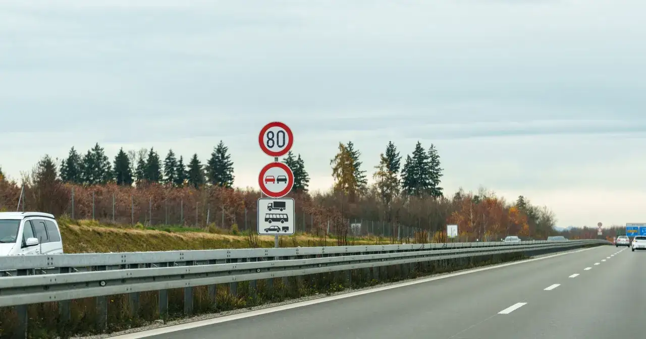 Znaki drogowe informują, czy w Niemczech na autostradach są ograniczenia prędkości. Widoczny znak 80 km/h i zakaz wyprzedzania dla ciężarówek.
