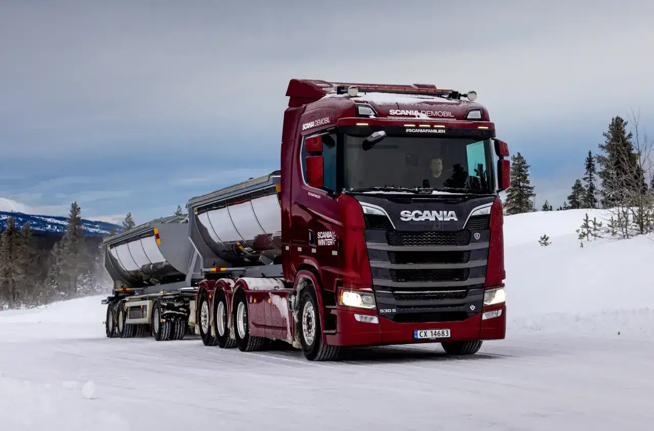 Czerwony Scania z dwiema przyczepami na zaśnieżonej drodze. Zastanawiasz się, ile waży tir z przyczepą? Ten zestaw jest gotowy do pracy.