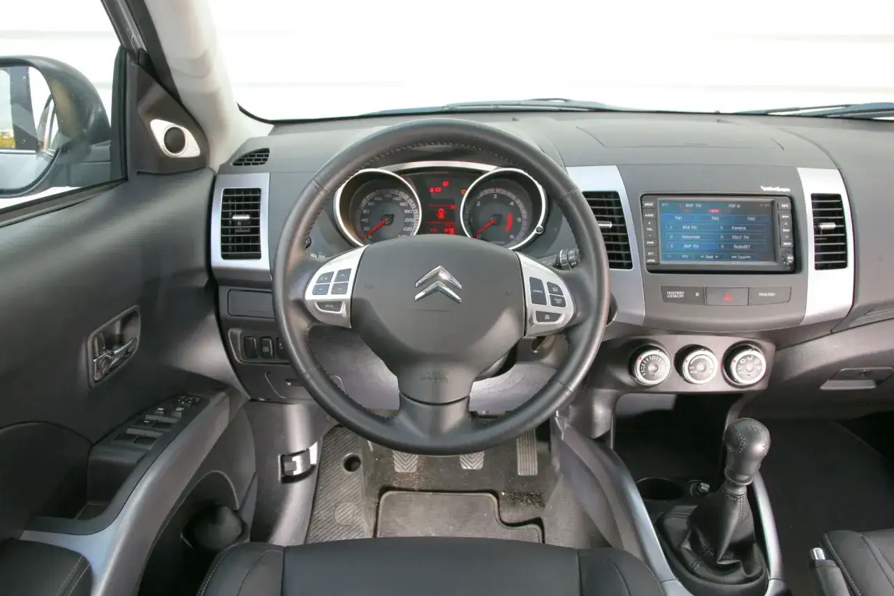 Wnętrze Citroena C-Crosser: kierownica, deska rozdzielcza z radiem i nawigacją, dźwignia zmiany biegów.