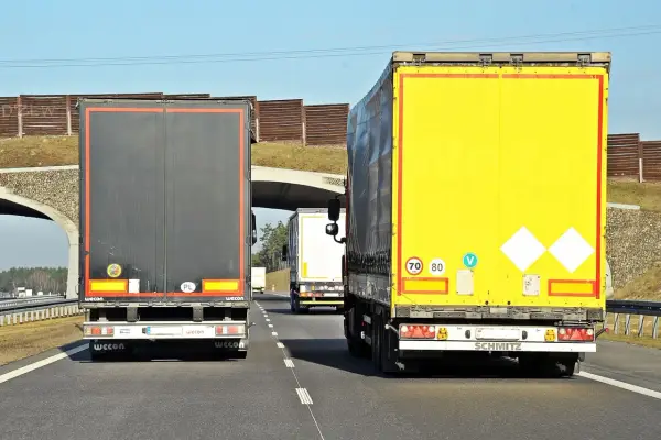 Na autostradzie jadą trzy tiry. Znak ograniczenia prędkości wskazuje, że tiry mogą jechać 70 lub 80 km/h.